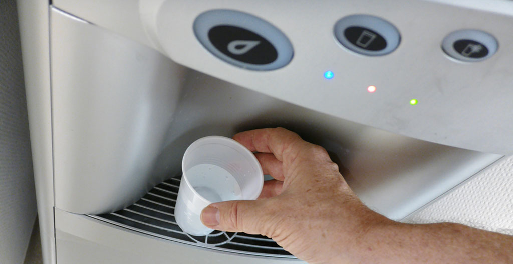 Profil d'une femme préparant une boisson chaude dans un espace de pause moderne avec lumière naturelle
