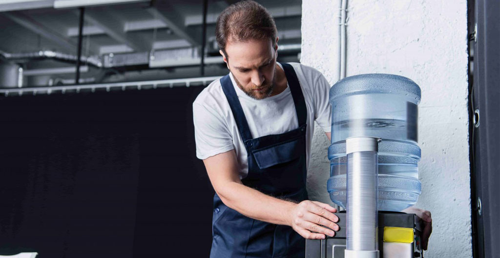 Vue d'ensemble d'un open space lumineux avec bureaux et un espace détente visible en arrière-plan